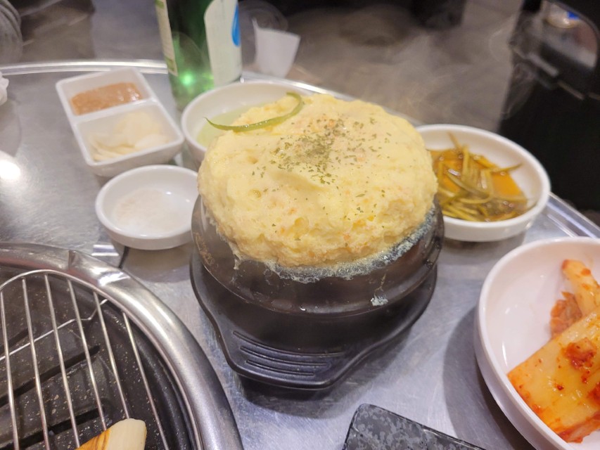 김이 나는 부드러운 뚝배기 계란찜, 다양한 한식 반찬 식탁.