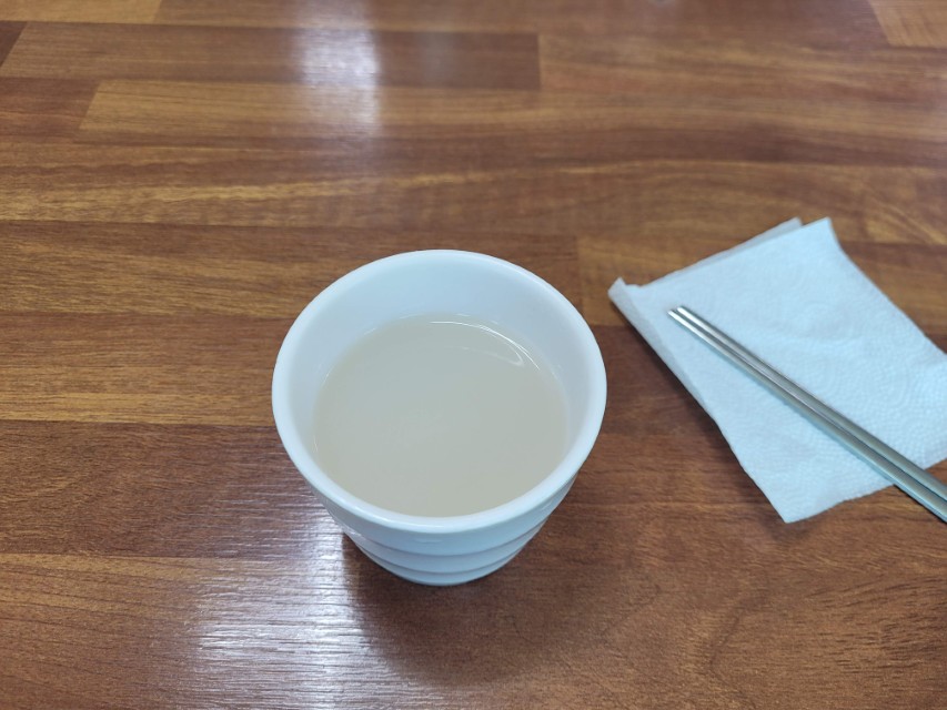 나무 탁자 위 하얀 사발 막걸리, 냅킨 위 젓가락