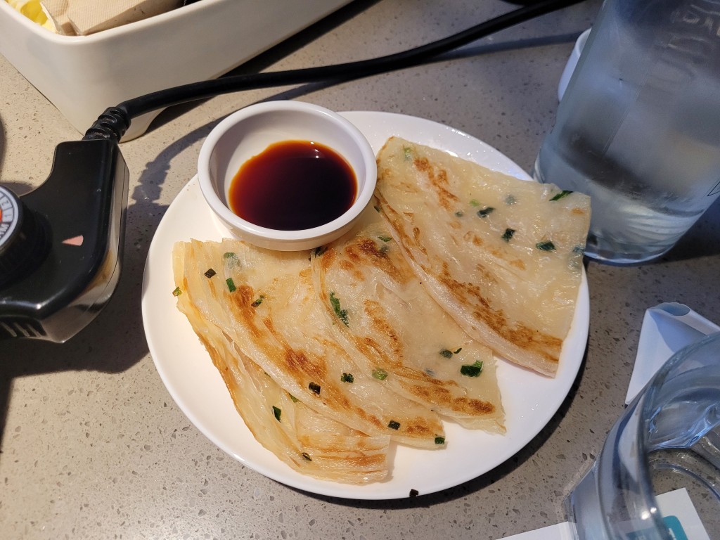 흰 접시 위 바삭한 총유병, 작은 간장 그릇, 흐릿한 물잔