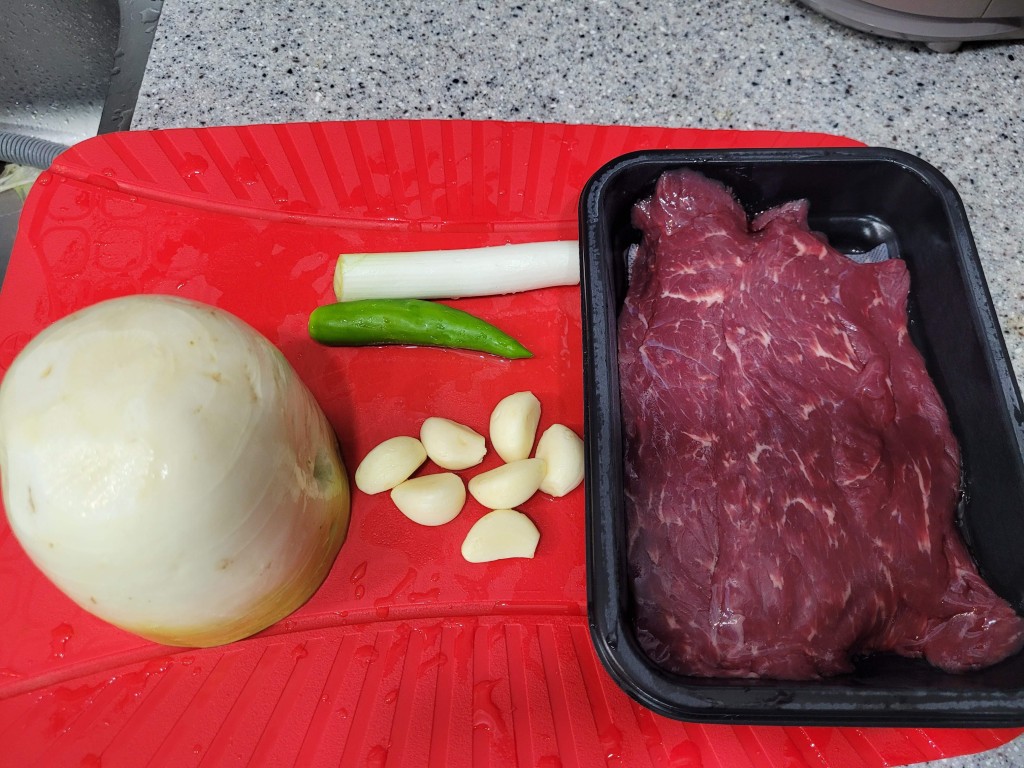 빨간 도마 위 생 소고기, 양파, 마늘, 고추, 대파