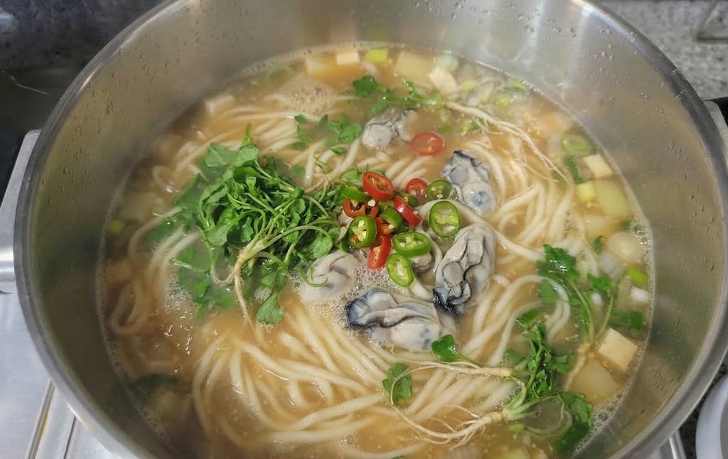 뜨거운 냄비 굴 칼국수, 신선한 미나리, 홍고추 청고추 고명