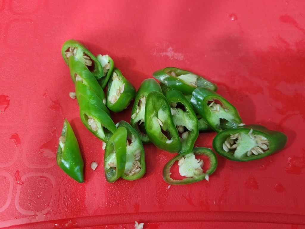 신선한 썰린 초록 고추 씨앗 빨간 도마 요리 재료