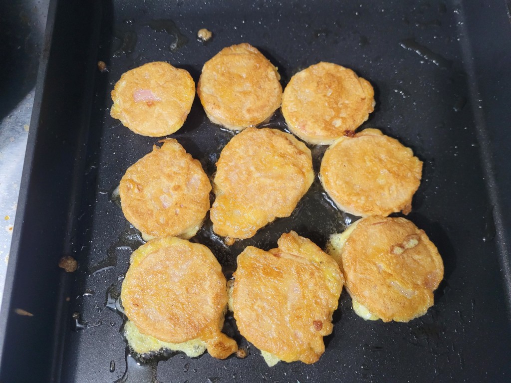 검은 프라이팬에 노릇하게 익는 동그랑땡 여러 개.