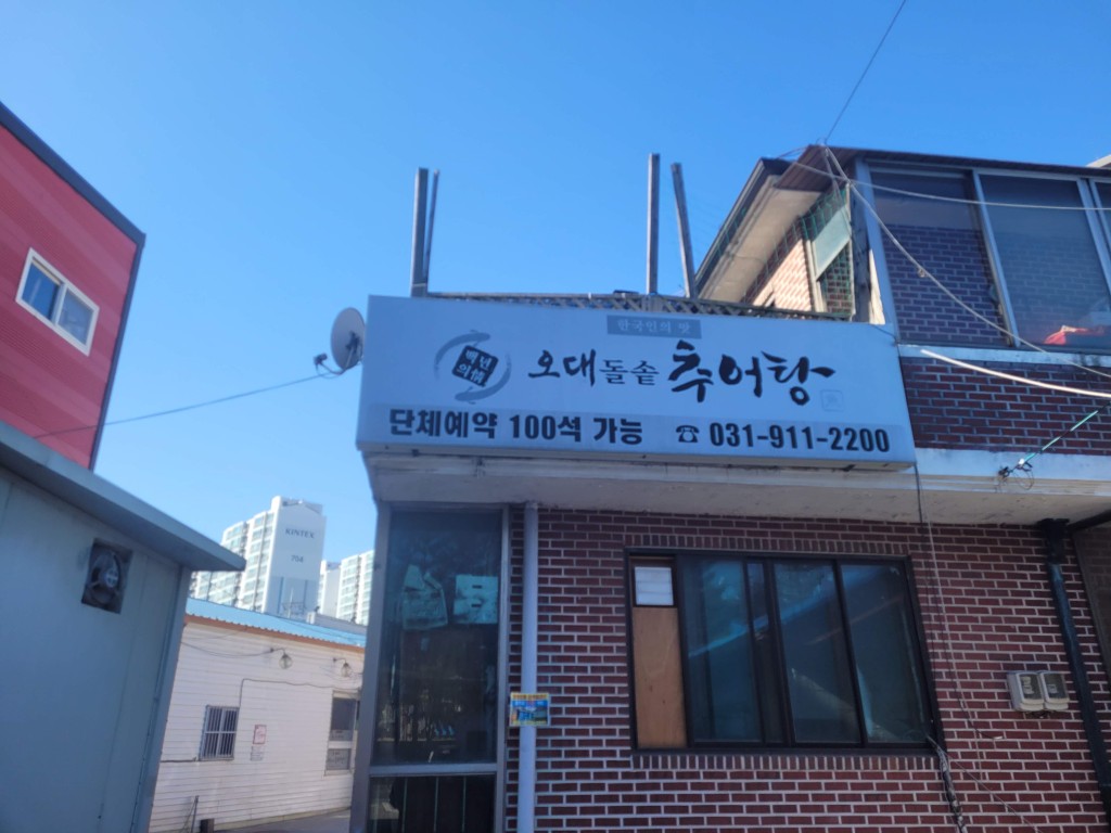 오대돌솥 추어탕 간판, 붉은 벽돌 건물, 맑은 하늘 배경