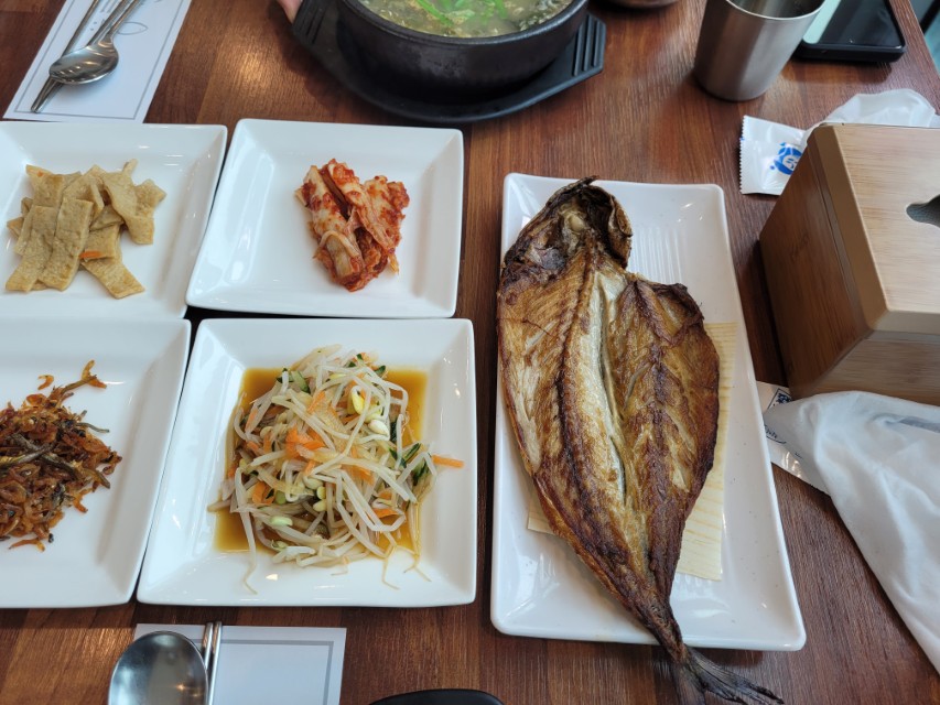 식탁 위 노릇한 생선구이, 다양한 한식 반찬, 따뜻한 국