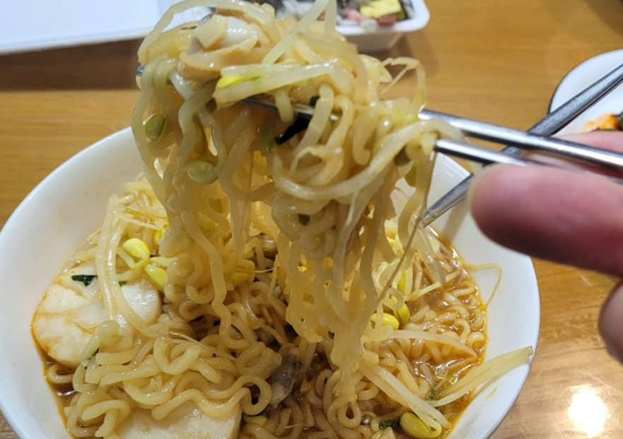 젓가락으로 매콤한 라면 면발, 콩나물, 어묵 들어 올리는 중