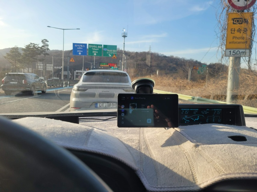 차량 대시보드에서 본 고속도로, 음악 재생 폰, 앞 차량, 도로 표지판