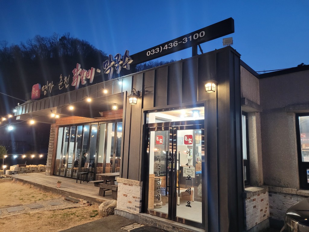 명가 춘천 닭갈비 막국수 식당 야경, 밝은 외부 조명과 데크.