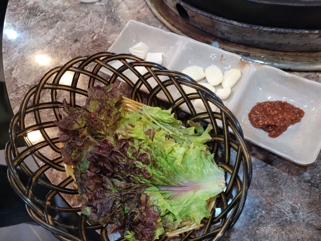 싱싱한 상추 바구니, 깐마늘, 매콤한 쌈장, 어두운 테이블
