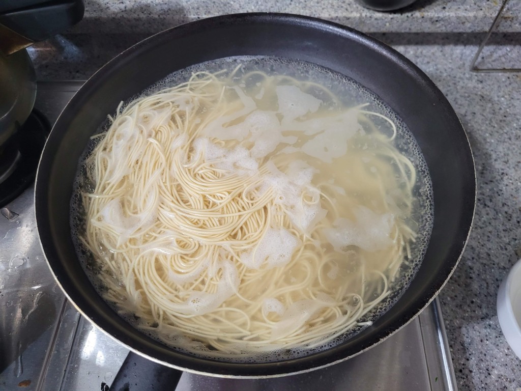 냄비 안 끓는 물 거품 속 연한 노란색 면발