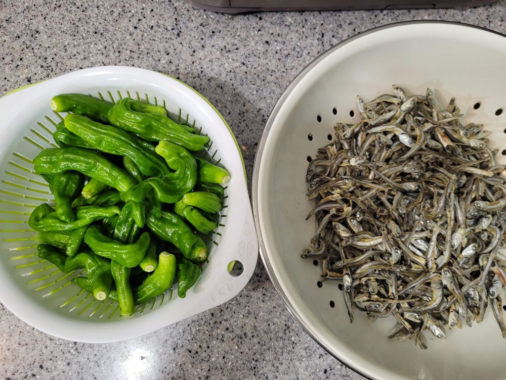 주름진 초록 꽈리고추와 작게 말린 은빛 멸치