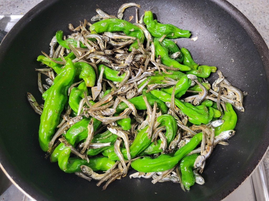 검은 프라이팬 속 노릇하게 익는 꽈리고추 멸치 볶음