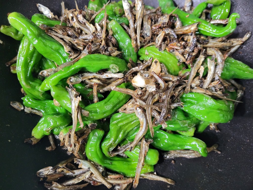 검은 팬 안 꽈리고추와 멸치 볶음, 마늘 조각 포함