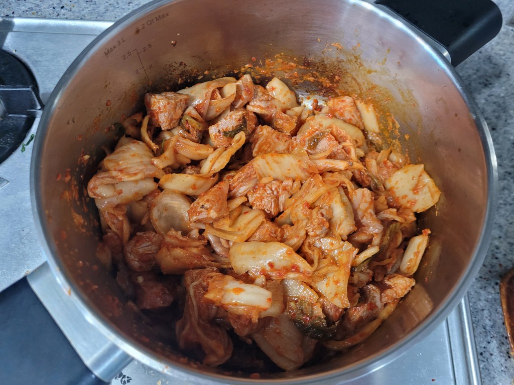 스텐 냄비 속 매콤한 김치, 돼지고기, 양파 볶음 요리