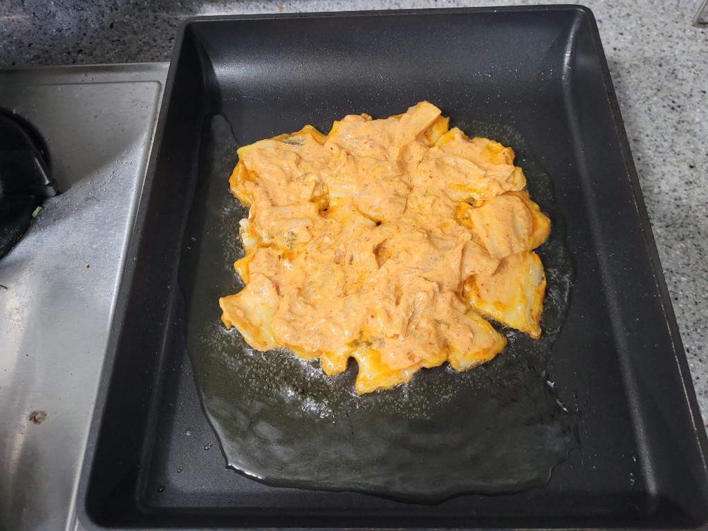 검은 조리 팬에 김치전 반죽 지글지글 익는 중