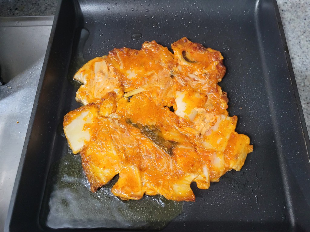 검은 프라이팬 위 매콤한 빨간 양념 생선구이 조리