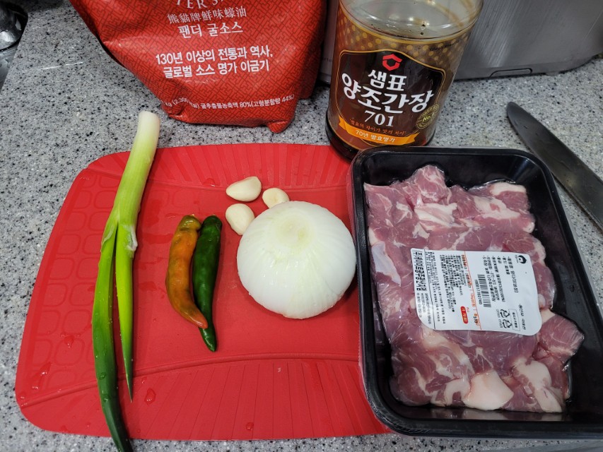 빨간 도마 위 돼지고기, 양파, 마늘, 파, 고추, 간장, 굴소스