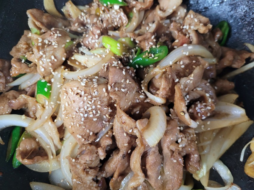 참깨 뿌려진 양파, 고추 곁들인 고기 볶음 요리