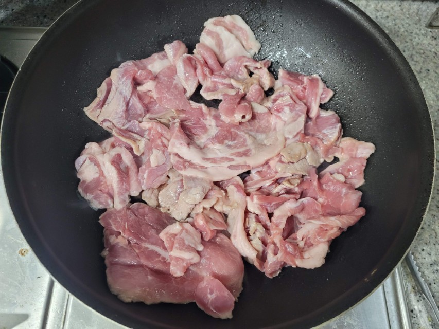 검은 팬에 얇게 썰어 담긴 신선한 돼지고기 삼겹살
