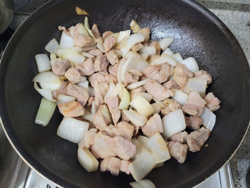 노릇하게 익어가는 깍둑썰기 돼지고기 양파 프라이팬 볶음 요리