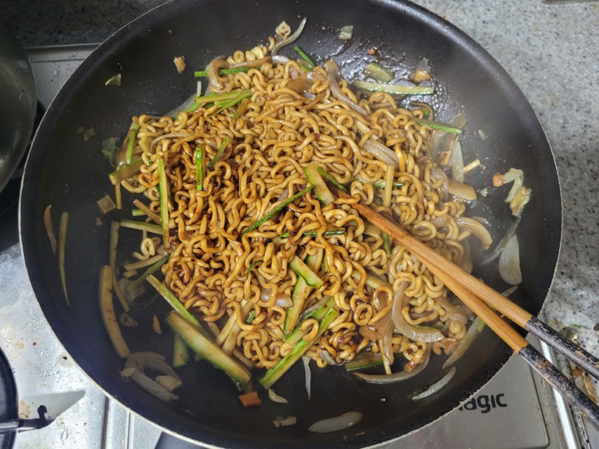 검은 팬 속 볶음 자장면, 오이, 양파, 젓가락
