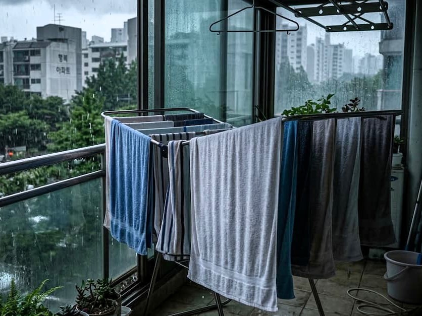 비 내리는 도시 발코니, 건조대에 걸린 다양한 색깔 수건
