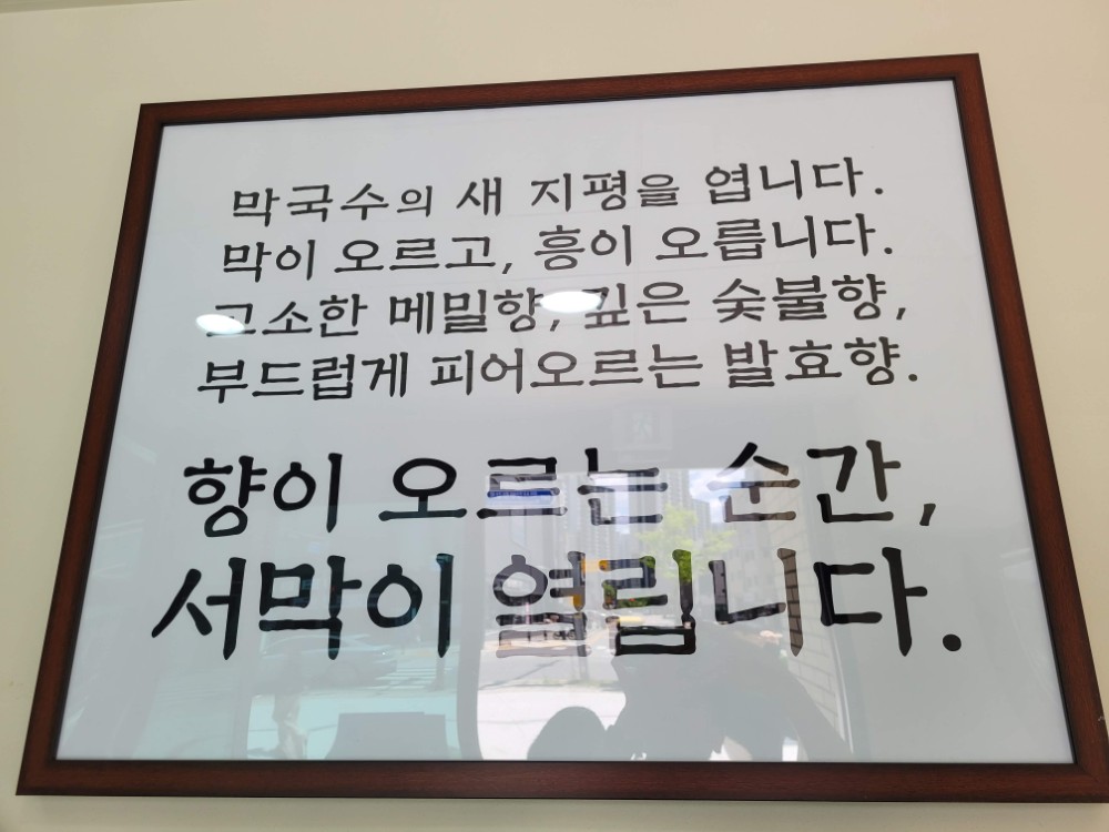 액자 속 한글 글귀, 막국수 메밀, 숯불, 발효향 상세 묘사.