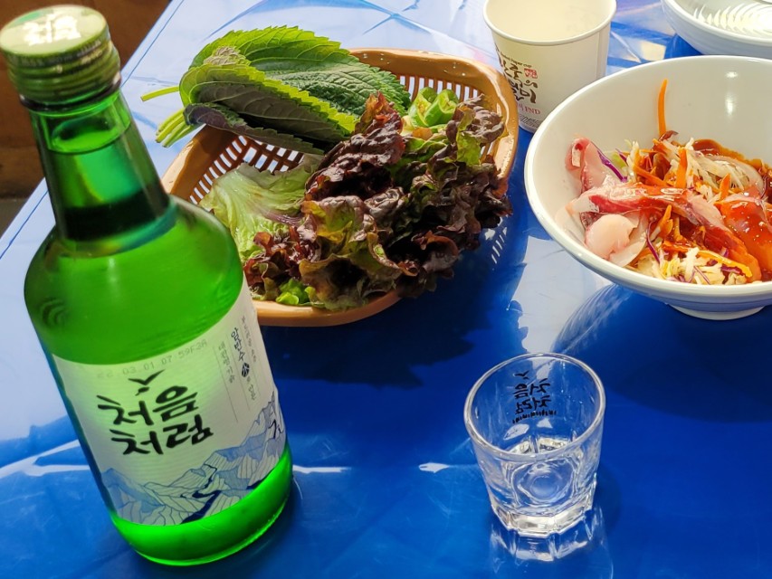 파란 식탁 위 처음처럼 소주병, 쌈채소, 신선한 회무침