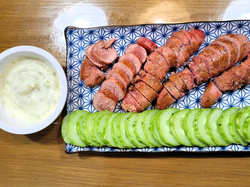 패턴 접시 위 구운 명란, 얇게 썬 오이, 곁들인 크림 소스