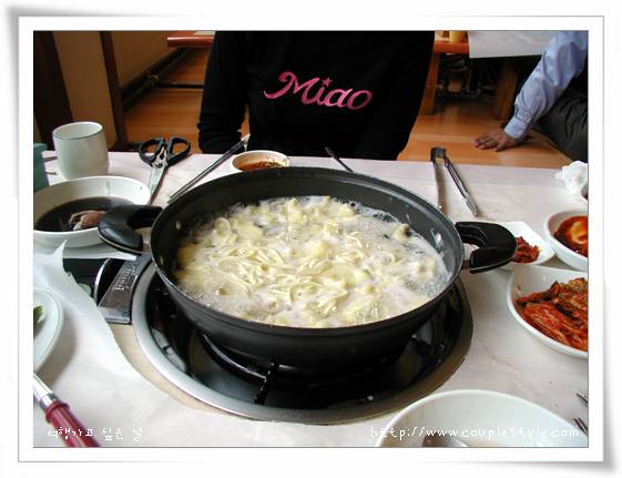 식탁 위 끓는 수제비 냄비, 김치와 다양한 한식 반찬