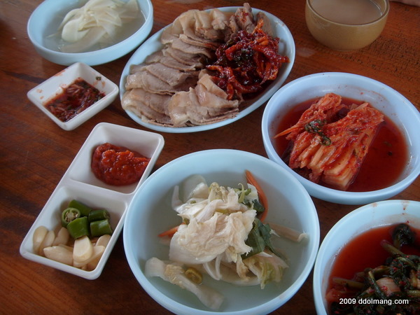 보쌈 요리: 썰린 돼지고기, 배추김치, 백김치, 마늘, 고추, 소스.