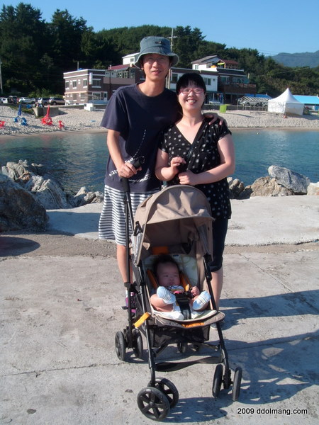 가족 해변 여행, 유모차 아기와 미소 짓는 부부