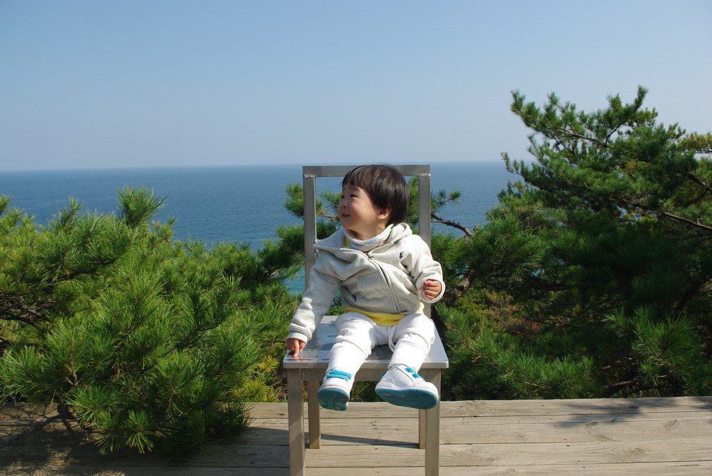 금속 의자 앉아 푸른 바다 소나무 보는 아이
