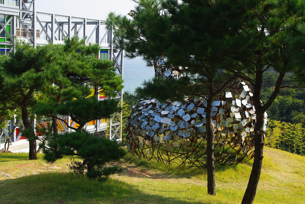 녹색 소나무, 금속 명판 구 조각, 다채로운 창문 건물, 먼 바다