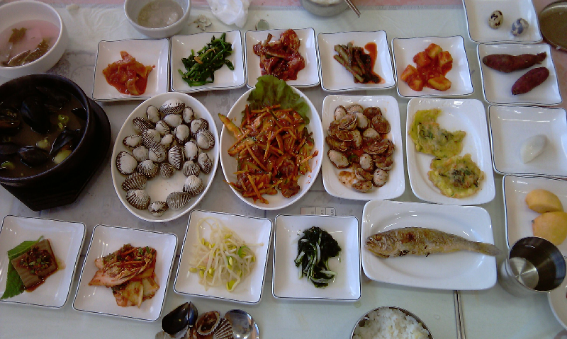 한국 전통 해산물 진수성찬, 다양한 반찬, 꼬막, 생선구이, 조개탕