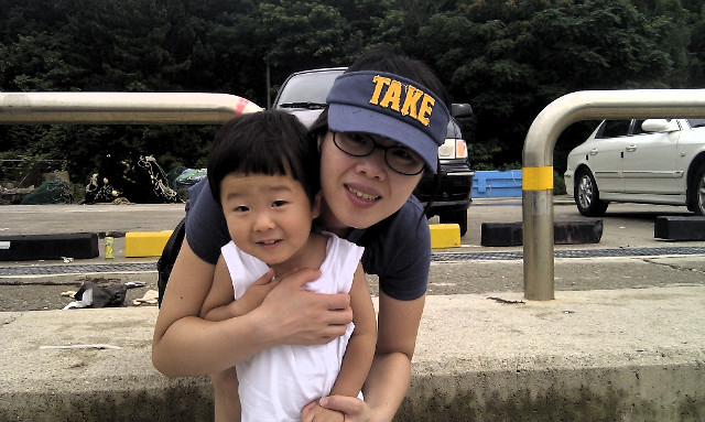 웃는 성인 선캡 어린 아이 안고 있는 야외 차량 배경