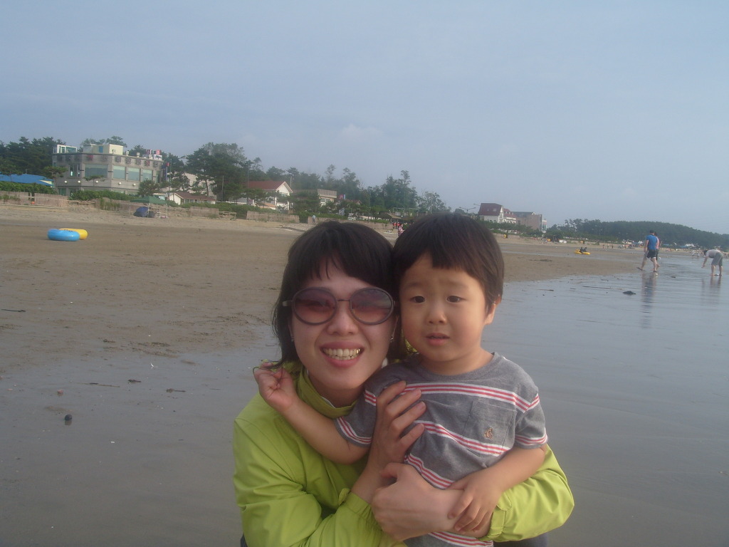 해변가 선글라스 어른, 아이 품에 안고 밝게 미소