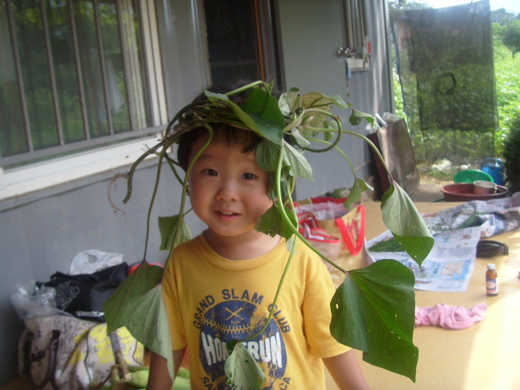 덩굴 왕관 쓴 미소 짓는 아이, 노란 셔츠, 야외 배경